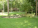 Backyard landscape design with natural stone planters filled with a variety of woodland plantings.